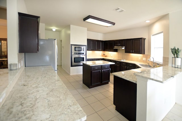 5315 Summit Knoll Trl, Sachse, TX 75048 - kitchen featuring appliances with stainless steel finishes, a sink, tasteful backsplash, light stone counters, and under cabinet range hood