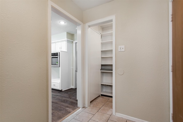 7102 Timberline Dr, Rowlett, TX 75089 - hallway with light tile patterned floors, baseboards, and a textured wall