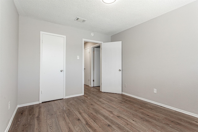 7102 Timberline Dr, Rowlett, TX 75089 - unfurnished bedroom with wood finished floors, baseboards, and a textured ceiling