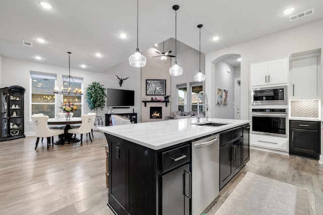 507 N Eagle Point Rd, Van Alstyne, TX 75495 - kitchen with appliances with stainless steel finishes, a sink, dark cabinetry, arched walkways, and light wood finished floors