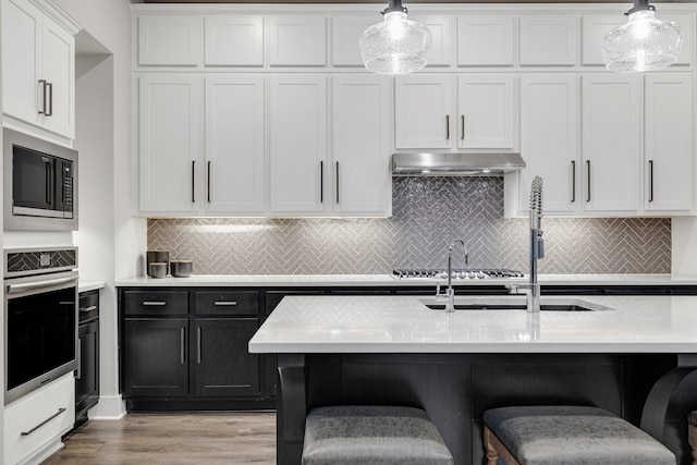 507 N Eagle Point Rd, Van Alstyne, TX 75495 - kitchen with stainless steel oven, built in microwave, under cabinet range hood, light countertops, and white cabinets