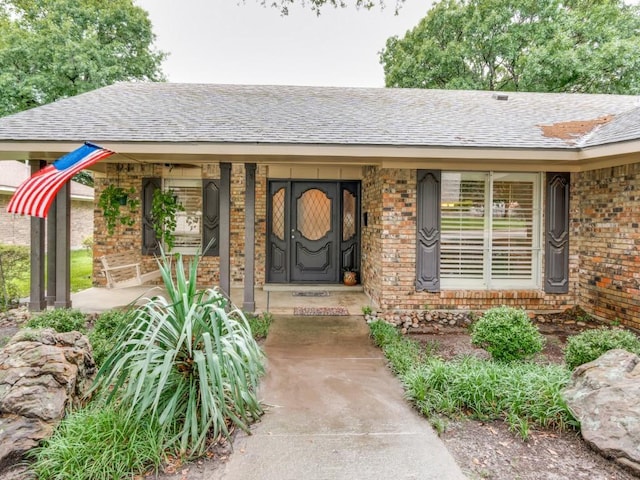 12151 Crestline Ave, Dallas, TX 75244 - view of exterior entry featuring brick siding, covered porch, and roof with shingles