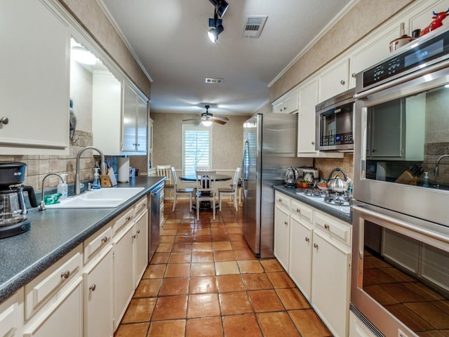 12151 Crestline Ave, Dallas, TX 75244 - kitchen featuring appliances with stainless steel finishes, backsplash, a sink, dark countertops, and crown molding