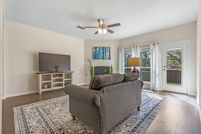 3932 Oak Creek Cir, Denison, TX 75020 - living room featuring ceiling fan, wood finished floors, a glass covered fireplace, and baseboards