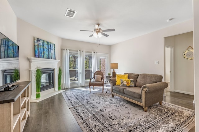 3932 Oak Creek Cir, Denison, TX 75020 - living area with a glass covered fireplace, ceiling fan, dark wood-type flooring, and baseboards