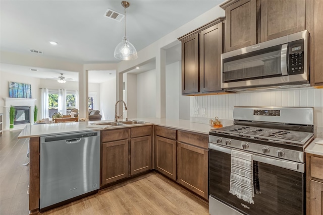 3932 Oak Creek Cir, Denison, TX 75020 - kitchen with appliances with stainless steel finishes, a peninsula, a sink, light countertops, and light wood-style flooring