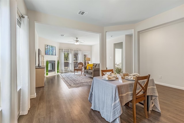 3932 Oak Creek Cir, Denison, TX 75020 - dining space with dark wood-style flooring, baseboards, ceiling fan, and a glass covered fireplace