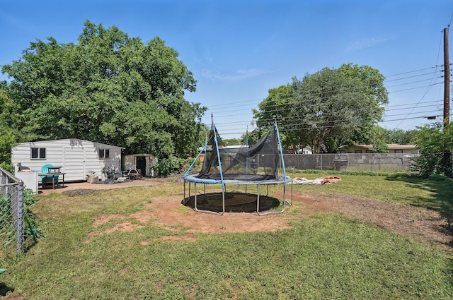 view of yard with a trampoline, an outbuilding, and a shed