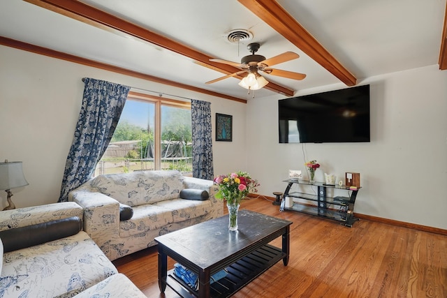 living area featuring beamed ceiling, baseboards, ceiling fan, and wood finished floors