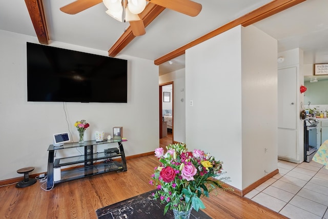 living room with a ceiling fan, beam ceiling, baseboards, and wood finished floors