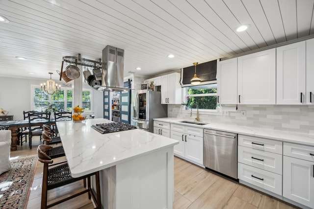 8538 Grenadier Dr, Dallas, TX 75238 - kitchen featuring appliances with stainless steel finishes, a sink, island range hood, a breakfast bar area, and healthy amount of natural light