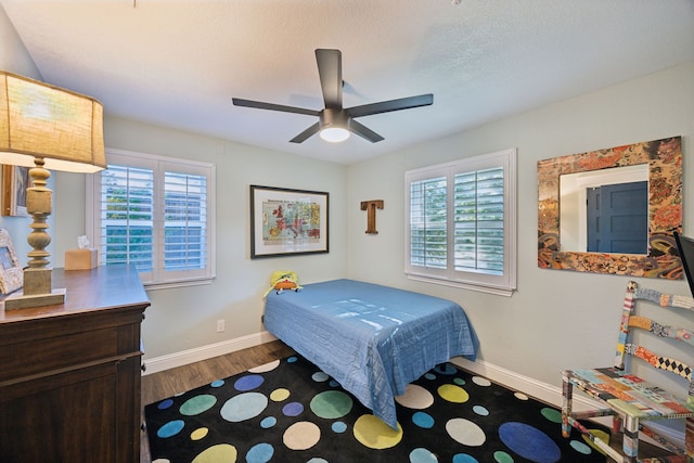8538 Grenadier Dr, Dallas, TX 75238 - bedroom featuring multiple windows, dark wood-type flooring, baseboards, and ceiling fan
