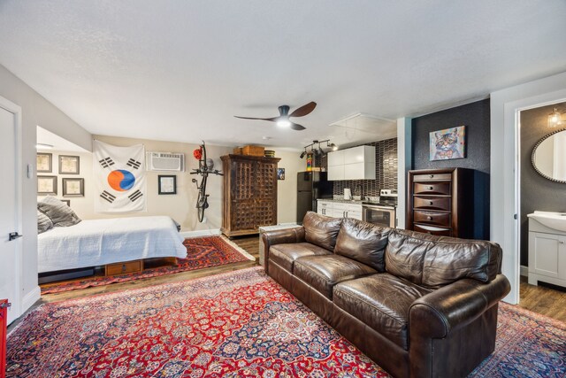 8538 Grenadier Dr, Dallas, TX 75238 - bedroom featuring wood finished floors, freestanding refrigerator, a wall unit AC, and baseboards