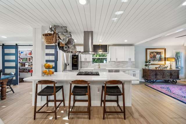 8538 Grenadier Dr, Dallas, TX 75238 - kitchen with stainless steel appliances, a barn door, white cabinetry, island exhaust hood, and a kitchen island