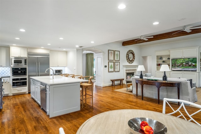 4710 Bobbitt Dr, Dallas, TX 75229 - kitchen with built in appliances, a glass covered fireplace, ceiling fan, arched walkways, and recessed lighting