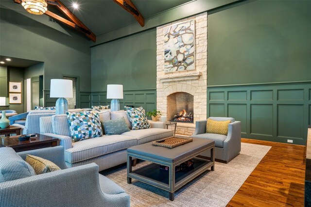 4710 Bobbitt Dr, Dallas, TX 75229 - living area featuring a decorative wall, beam ceiling, wood finished floors, a towering ceiling, and a stone fireplace