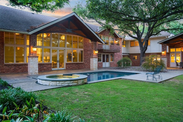 4710 Bobbitt Dr, Dallas, TX 75229 - back of house at dusk featuring french doors, a patio area, brick siding, and a lawn