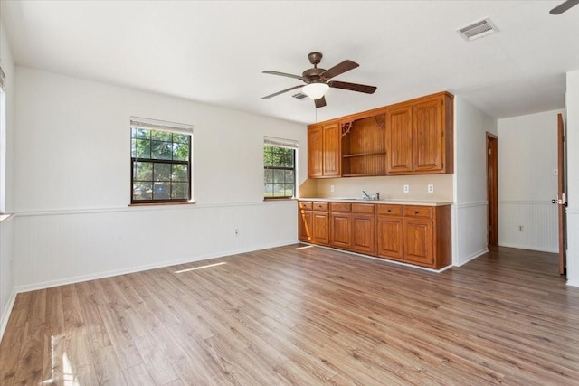 1345 Stillwater Rd, Waco, TX 76708 - kitchen with a ceiling fan, open shelves, light wood-style flooring, brown cabinetry, and light countertops