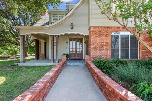 1345 Stillwater Rd, Waco, TX 76708 - property entrance featuring french doors, brick siding, a yard, a porch, and board and batten siding