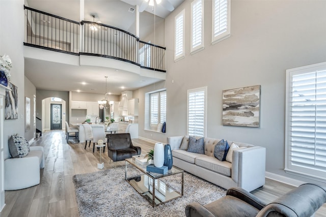 12523 Royal Oaks Ln, Farmers Branch, TX 75234 - living room featuring light wood finished floors, a high ceiling, arched walkways, baseboards, and healthy amount of natural light