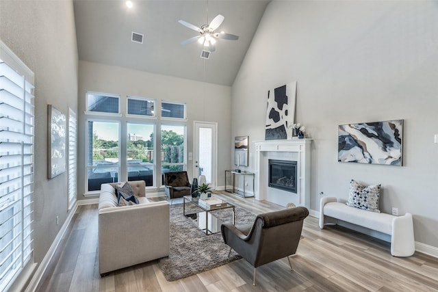 12523 Royal Oaks Ln, Farmers Branch, TX 75234 - living area featuring high vaulted ceiling, wood finished floors, a glass covered fireplace, a ceiling fan, and baseboards
