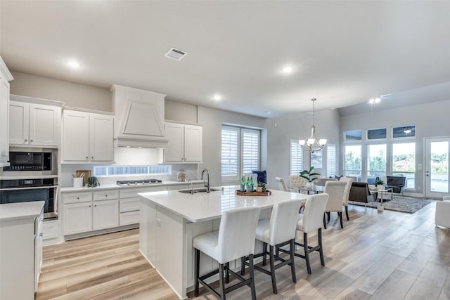 12523 Royal Oaks Ln, Farmers Branch, TX 75234 - kitchen featuring stainless steel appliances, a sink, custom range hood, light countertops, and a chandelier