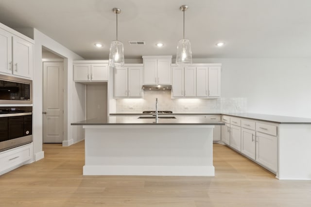 8289 Emsworth Dr, Dallas, TX 75231 - kitchen with stainless steel oven, built in microwave, decorative backsplash, white cabinets, and light wood finished floors