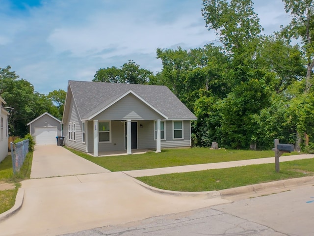 view of front of home with driveway, an outbuilding, a shingled roof, a garage, and a front yard