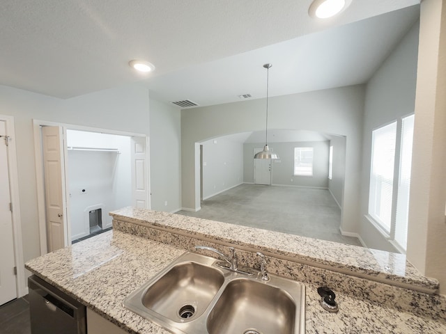 kitchen featuring a sink, stainless steel dishwasher, light stone countertops, pendant lighting, and carpet floors