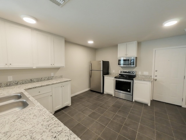 kitchen featuring stainless steel appliances, white cabinets, dark tile patterned floors, and recessed lighting