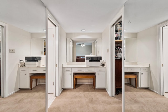 corridor featuring a desk, light carpet, and baseboards
