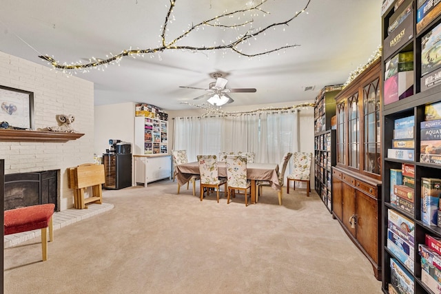 carpeted dining space featuring ceiling fan and a fireplace