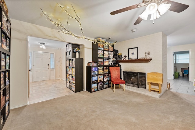 sitting room featuring a fireplace, carpet, a ceiling fan, and tile patterned flooring