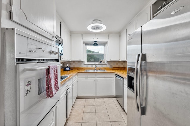 kitchen with appliances with stainless steel finishes, a sink, light countertops, tasteful backsplash, and white cabinetry