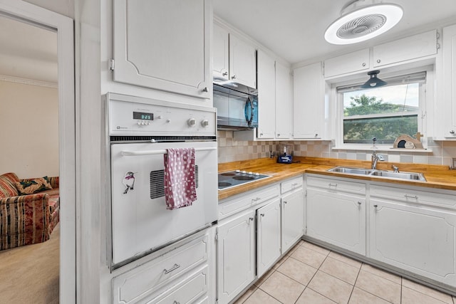 kitchen featuring oven, a sink, black microwave, electric cooktop, and white cabinets