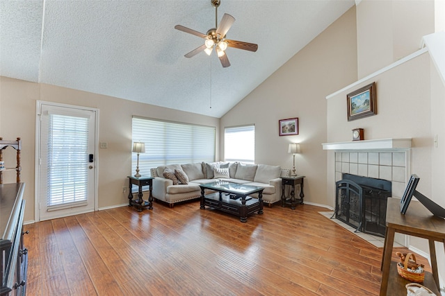 3817 Roman Ct, Plano, TX 75023 - living room featuring high vaulted ceiling, wood finished floors, a ceiling fan, healthy amount of natural light, and a tiled fireplace