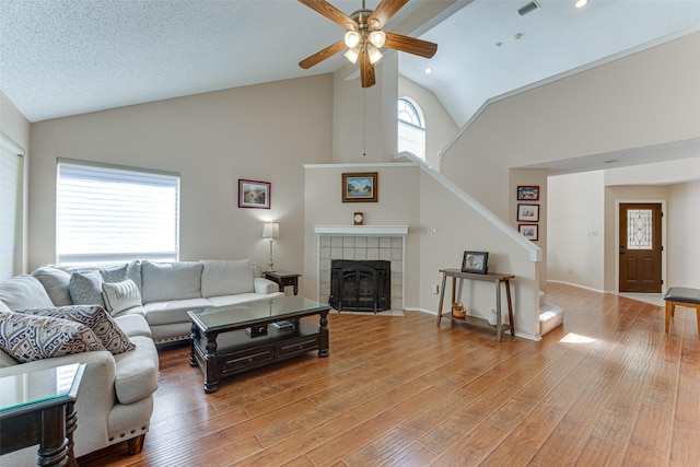 3817 Roman Ct, Plano, TX 75023 - living area with a ceiling fan, stairs, high vaulted ceiling, light wood-style floors, and a tiled fireplace