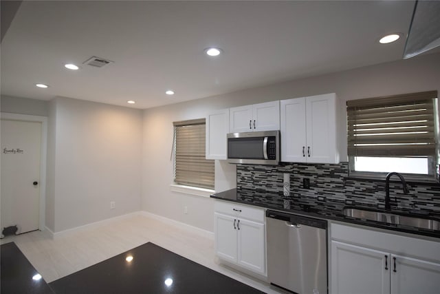 1524 Daywood Ln, Irving, TX 75061 - kitchen featuring appliances with stainless steel finishes, a sink, dark countertops, tasteful backsplash, and white cabinetry