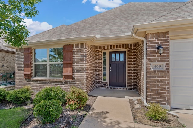 409 Bird Creek Dr, Little Elm, TX 75068 - property entrance featuring brick siding, a shingled roof, and an attached garage