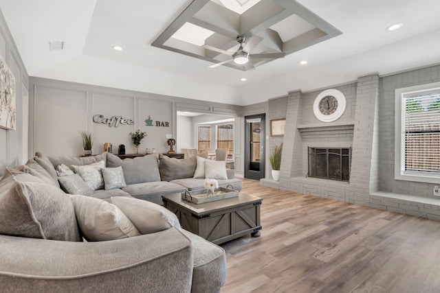 7108 Bermuda Ct, North Richland Hills, TX 76180 - living room with wood finished floors, recessed lighting, ceiling fan, a brick fireplace, and a skylight