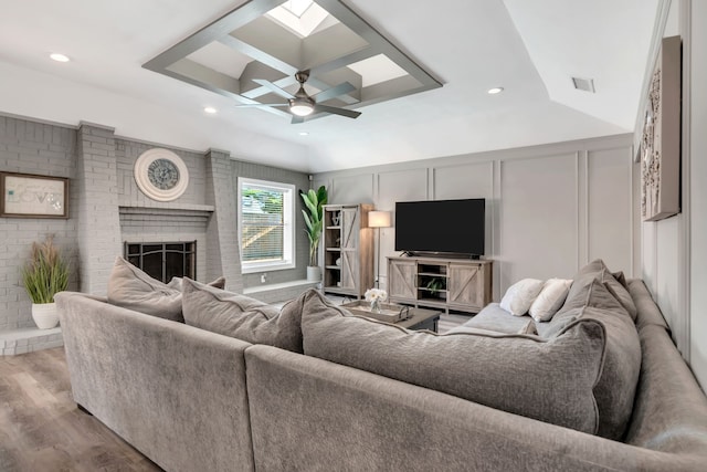 7108 Bermuda Ct, North Richland Hills, TX 76180 - living room with wood finished floors, ceiling fan, a decorative wall, a brick fireplace, and a skylight