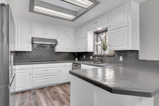 7108 Bermuda Ct, North Richland Hills, TX 76180 - kitchen featuring wall chimney range hood, a sink, a peninsula, appliances with stainless steel finishes, and tile countertops