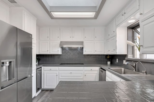 7108 Bermuda Ct, North Richland Hills, TX 76180 - kitchen featuring stainless steel appliances, wall chimney exhaust hood, tile countertops, a sink, and white cabinetry