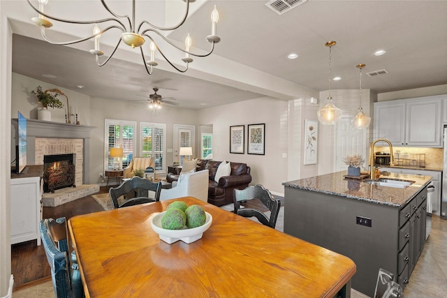 1704 Landon Ln, Mckinney, TX 75071 - dining room with a brick fireplace, recessed lighting, ceiling fan, baseboards, and a chandelier