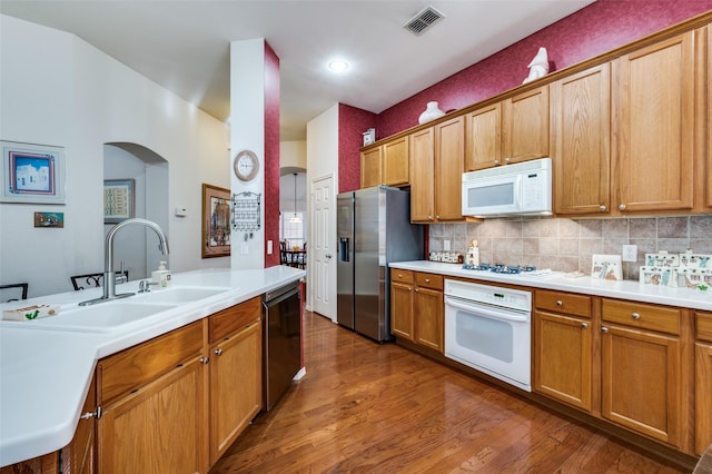 1699 Garrison Dr, Frisco, TX 75033 - kitchen with white appliances, a sink, dark wood-type flooring, light countertops, and arched walkways