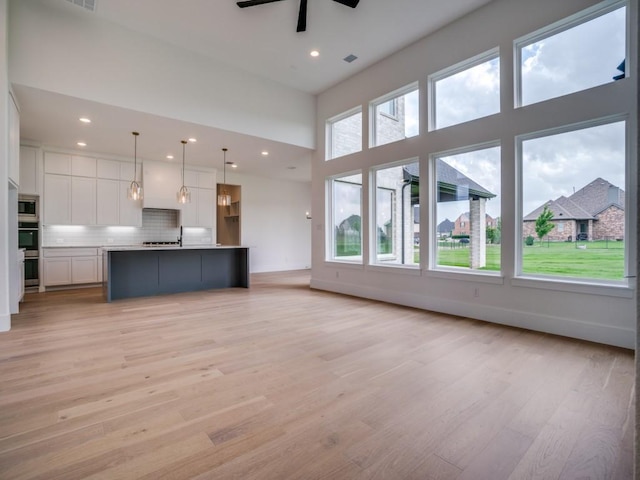 1045 Bent Tree Ln, Gunter, TX 75058 - unfurnished living room with a ceiling fan, light wood-style floors, a towering ceiling, recessed lighting, and baseboards