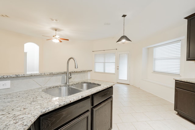 127 Wandering Dr, Forney, TX 75126 - kitchen with a sink, a ceiling fan, arched walkways, light tile patterned flooring, and light stone counters