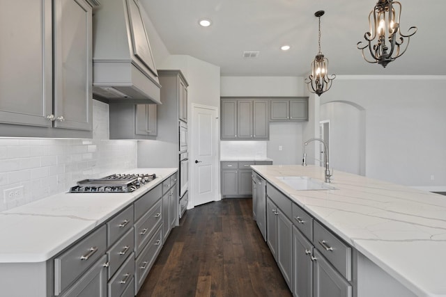 1038 Mickelson Dr, Granbury, TX 76048 - kitchen with gray cabinetry, custom range hood, appliances with stainless steel finishes, a sink, and light stone counters