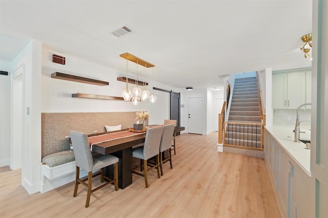 801 Edgefield Rd, Fort Worth, TX 76107 - dining room with a barn door, stairway, light wood finished floors, and baseboards