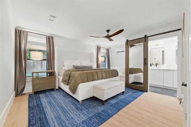 801 Edgefield Rd, Fort Worth, TX 76107 - bedroom featuring wood finished floors, a barn door, a ceiling fan, ensuite bath, and baseboards